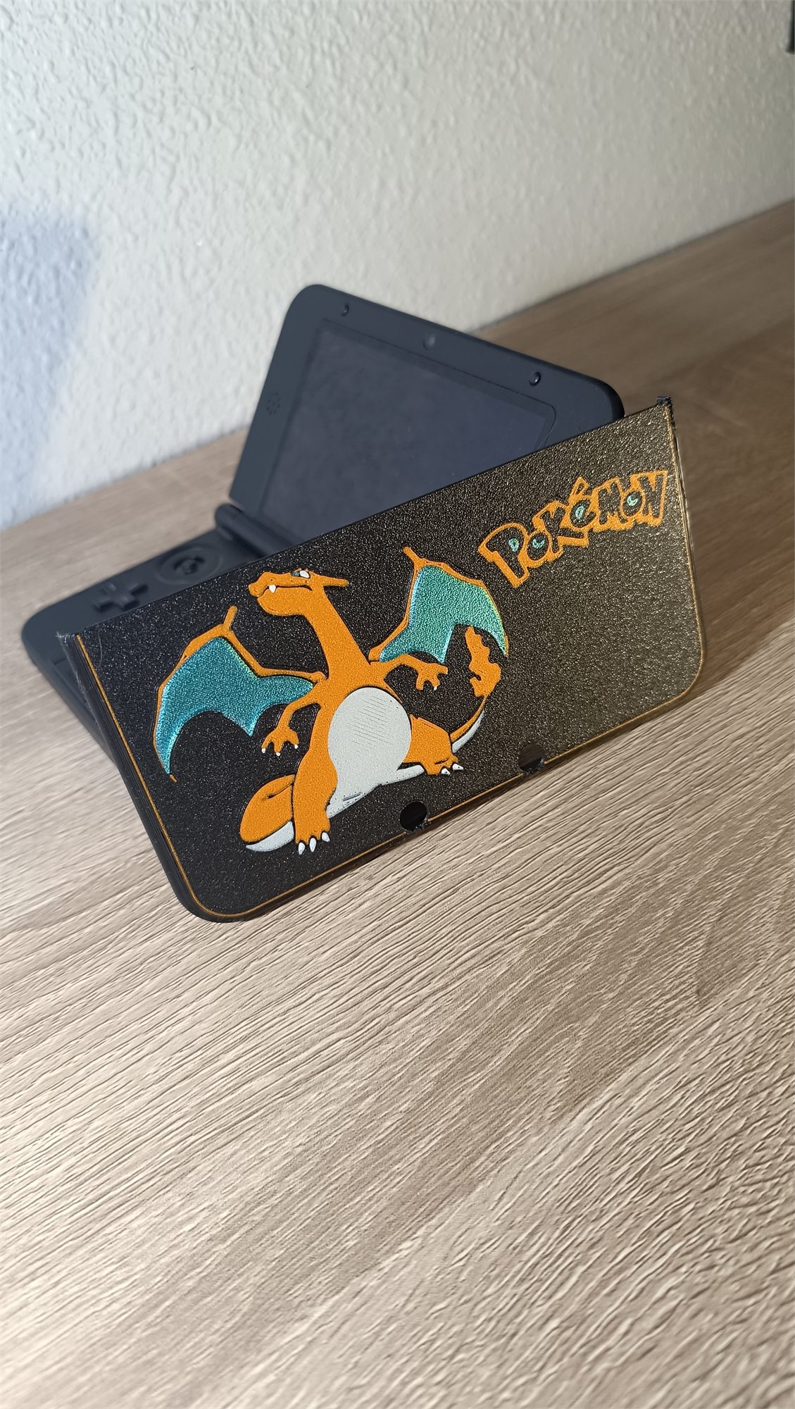 Carcasa Charizard apoyada sobre una Nintendo 3DS XL abierta